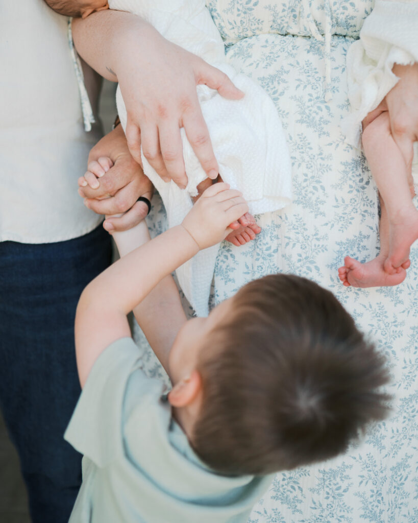 toddler touches toes of newborn sibling