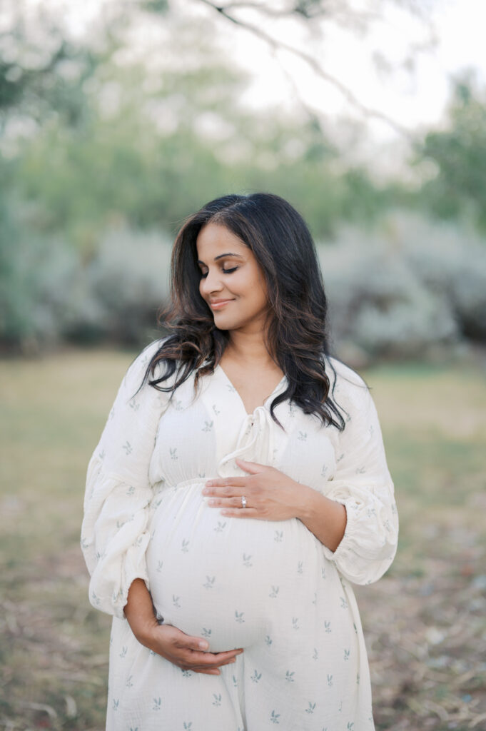 expecting mom looks calmly to side while holding baby bump