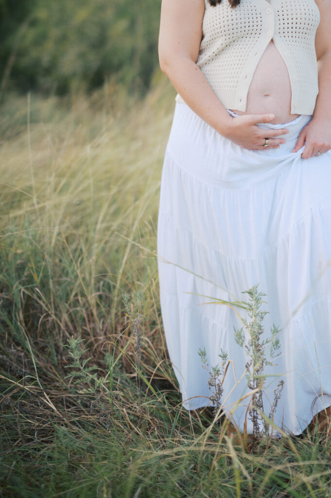 maternity photo of mom holding belly bump outdoors