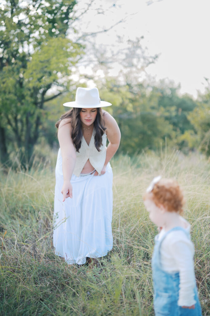 mom and little girl outside in field during maternity photos in fort worth