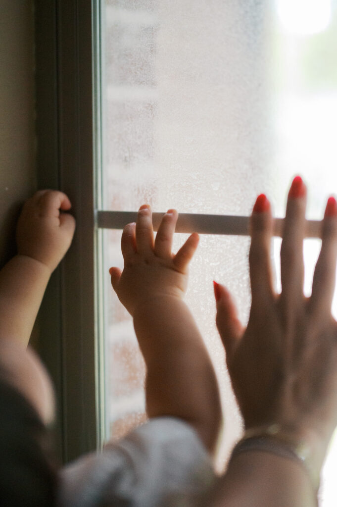 mom and baby hands on window pane