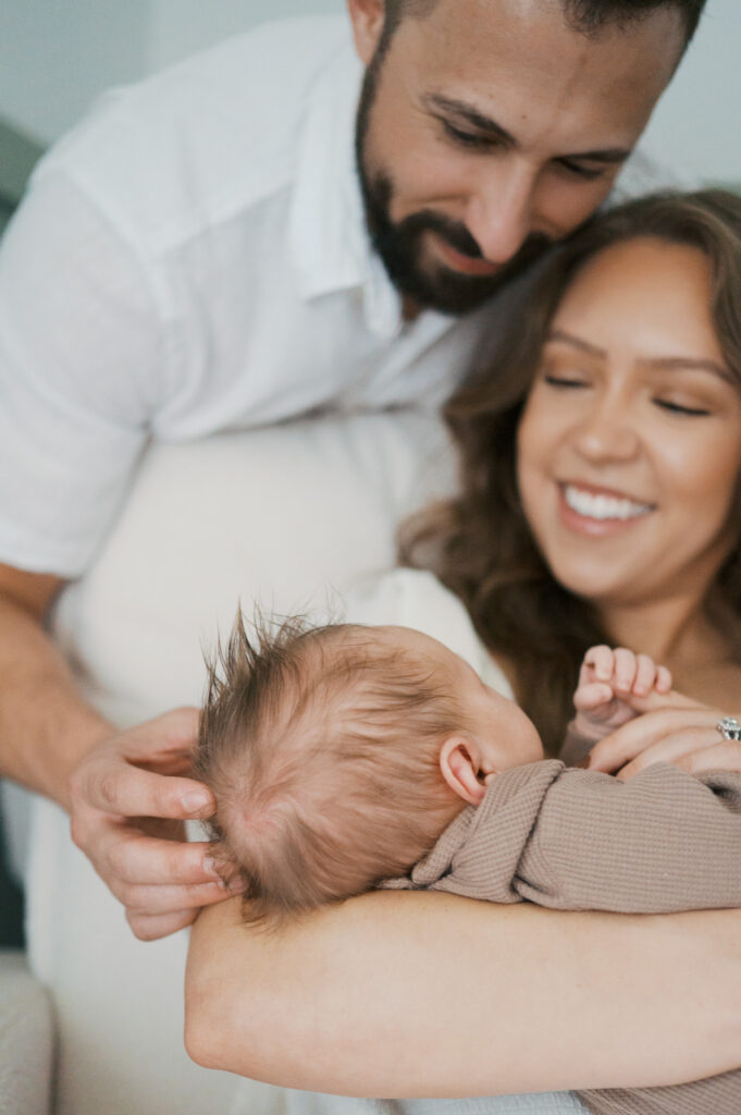 baby snuggles in mom's arms while both parents look down at it