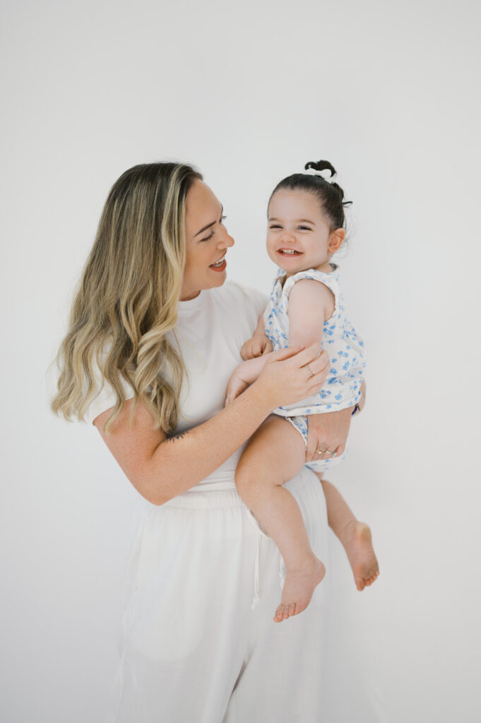 mom smiles at little girl during family photos in a fort worth studio