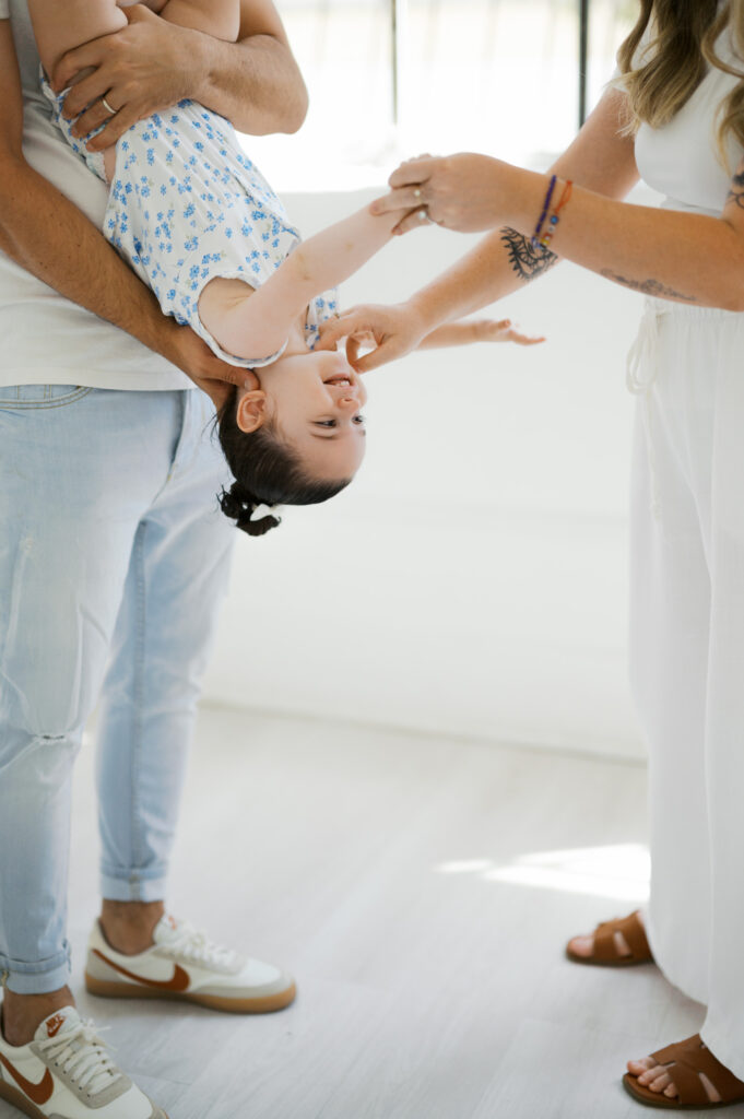 mom and dad play with daughter during family photos in studio