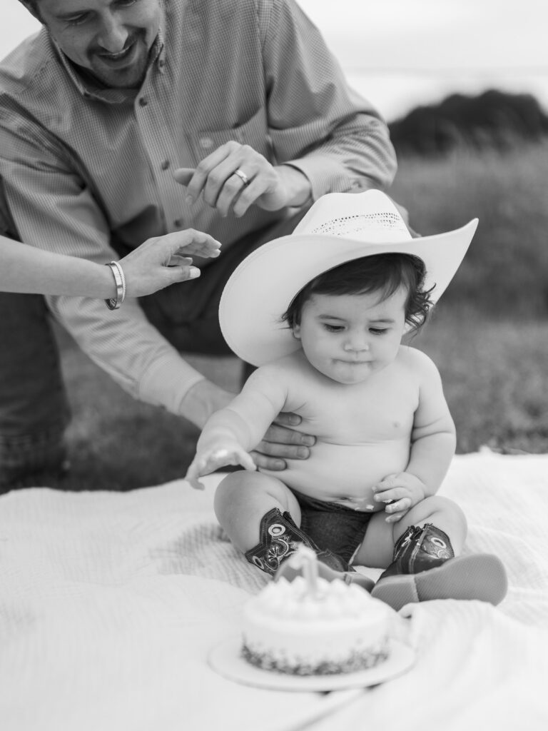 one year old reaches for birthday cake during milestone photos in benbrook texas