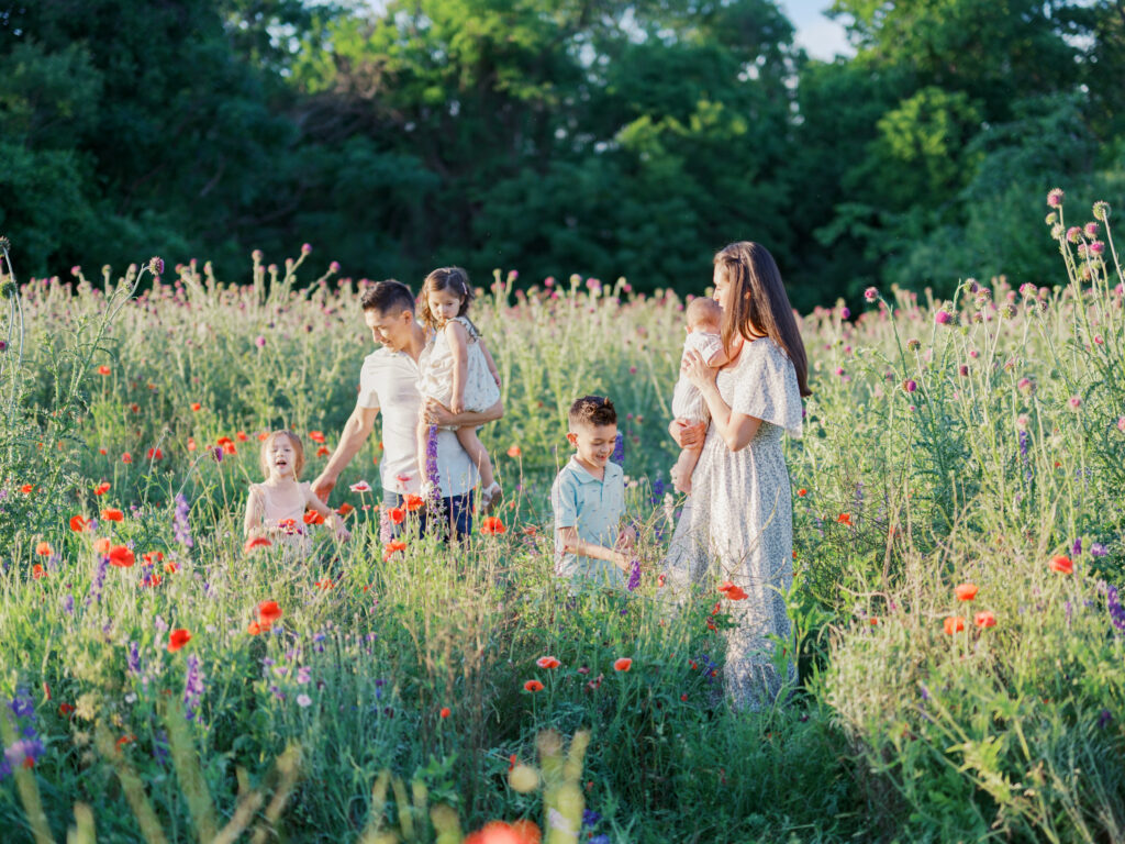 family of five plays in a wildflower field in DFW, mom looks back at family
