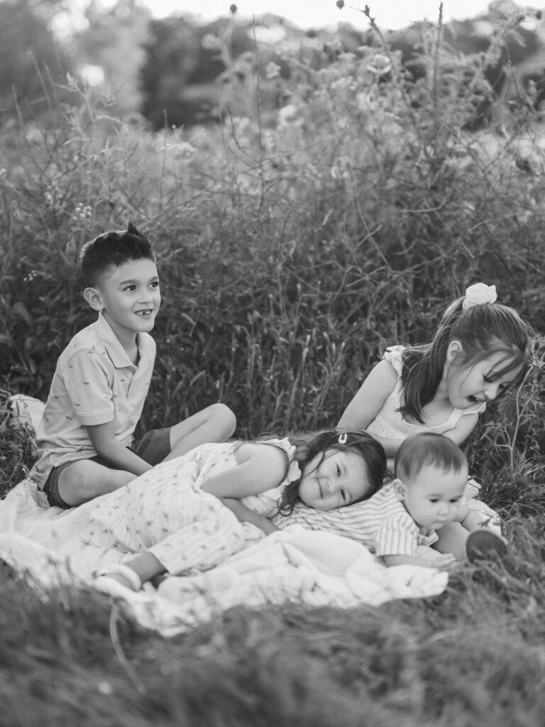 siblings pile on to each during outdoor family photos in spring in DFW