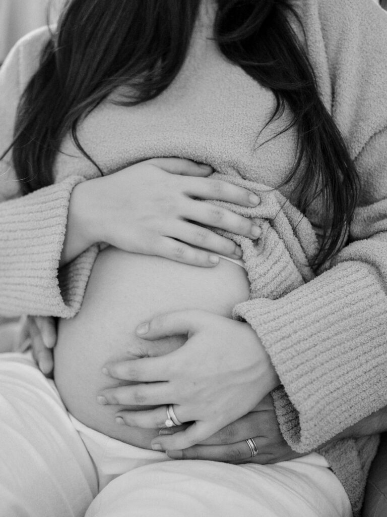 maternity photography in DFW, at home session with a black and white image of expecting parents touching baby bump