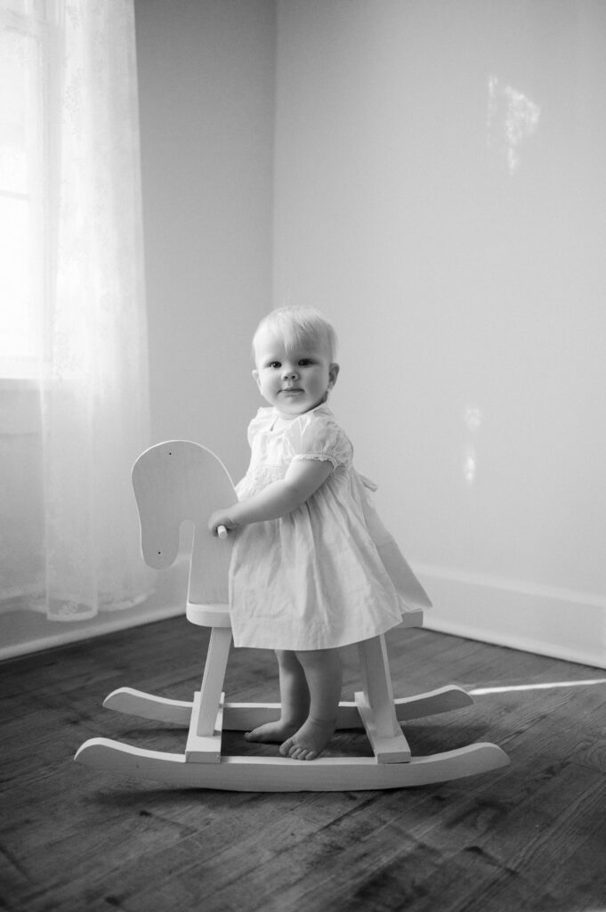 one year old looks at camera and while on rocking horse